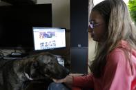 Ana-Maria Ciulcu pets Pedro, a dog rescued from a shelter, while observing her Facebook page in Bucharest April 12, 2014. Ana-Maria is just 13 years-old and she had the idea of using social media to find people willing to adopt a stray dog. Different from other children her age, she uses all her free time to save stray dogs. Her Facebook page turned into an adoption centre, very successful until now, with more than 150 dogs sent abroad to animal lovers mainly from Germany, Austria and Belgium. Picture taken April 12, 2014. REUTERS/Bogdan Cristel (ROMANIA - Tags: ANIMALS SOCIETY)