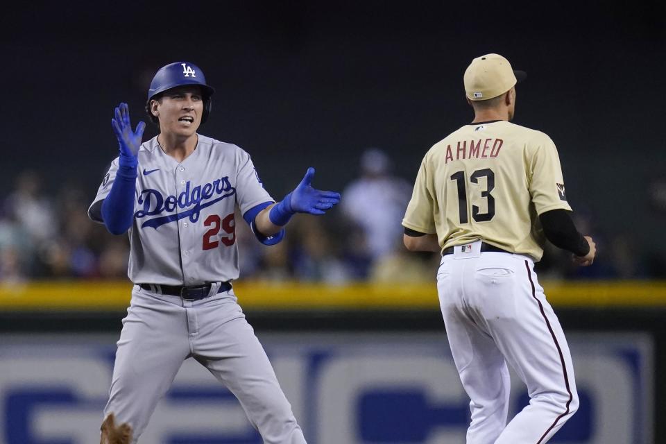 Los Angeles Dodgers' Andy Burns (29) celebrates his double against the Arizona Diamondbacks as Diamondbacks shortstop Nick Ahmed (13) waits for a late throw during the eighth inning of a baseball game Friday, June 18, 2021, in Phoenix. The Dodgers won 3-0. (AP Photo/Ross D. Franklin)