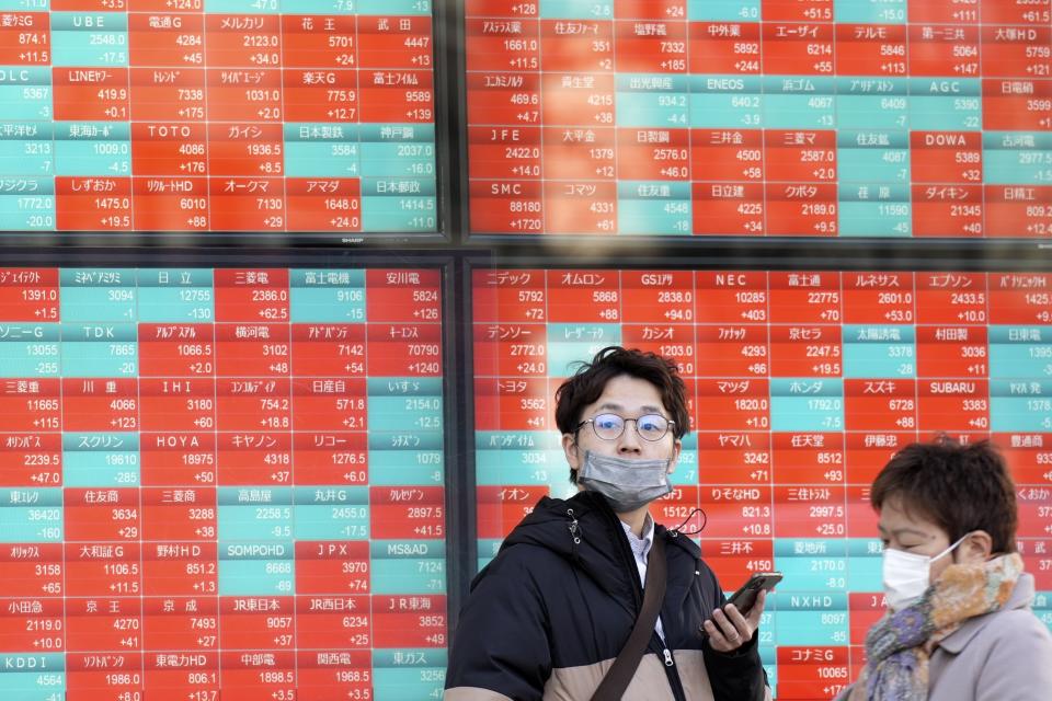 FILE - People stand in front of an electronic stock board showing Japan's stock prices at a securities firm Monday, Feb. 26, 2024, in Tokyo. Asian markets retreated Friday, March 15, with Hong Kong’s benchmark falling nearly 2%, after a mixed batch of data on the U.S. economy dashed hopes that easier interest rates are coming soon.(AP Photo/Eugene Hoshiko, File)