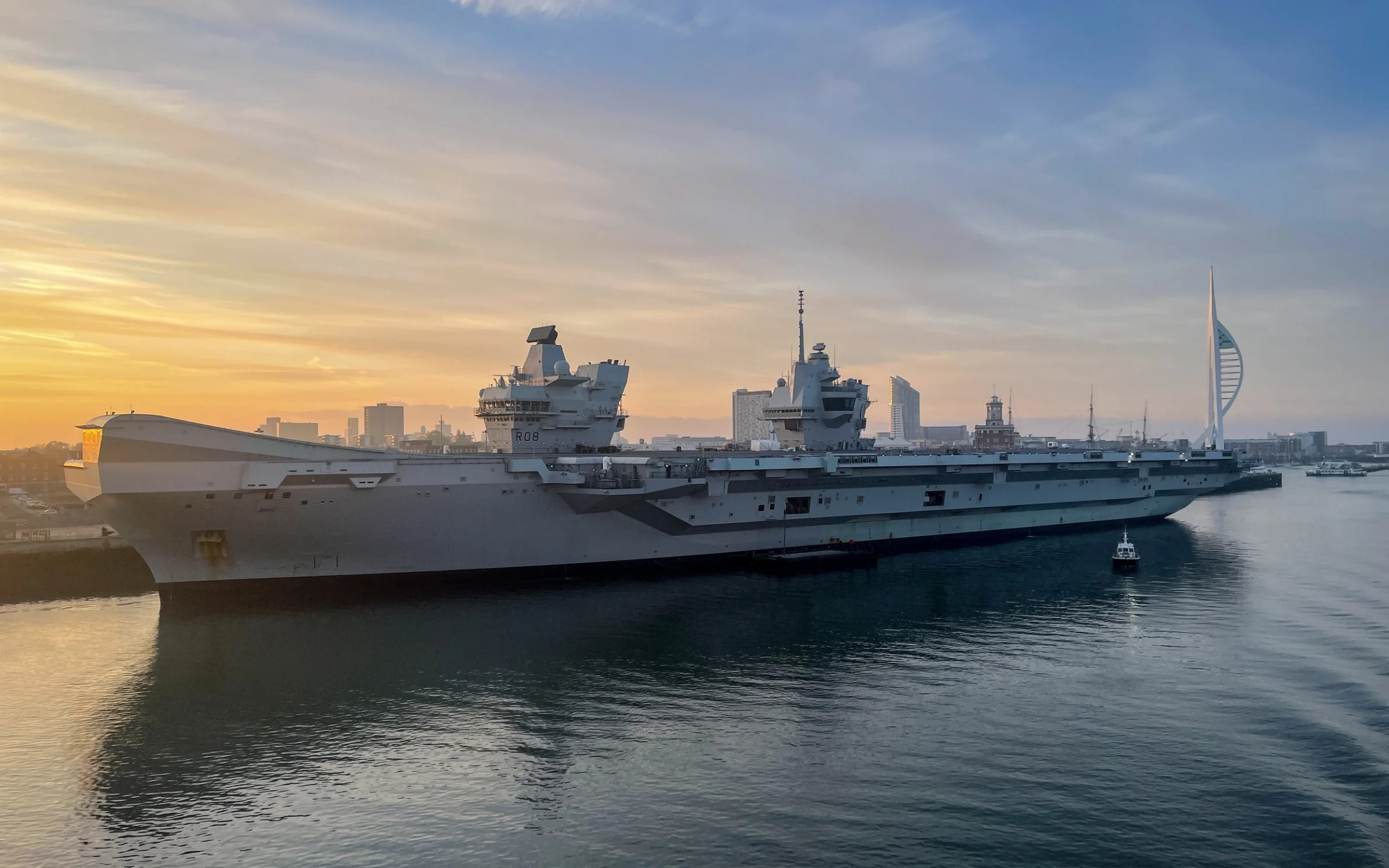 The sun rises behind the Royal Navy's HMS Queen Elizabeth aircraft carrier