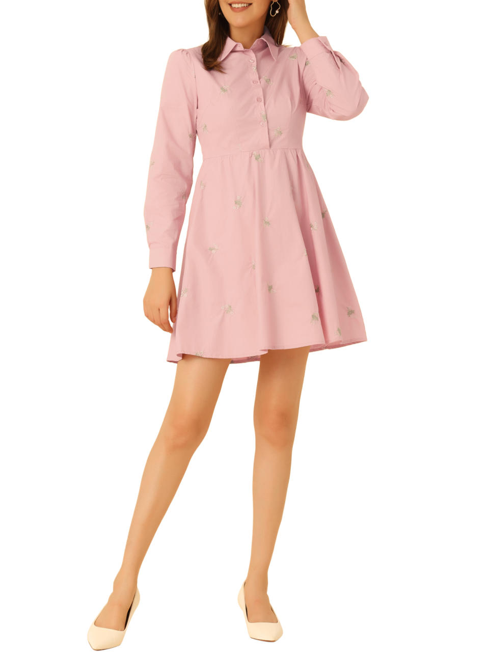 Person in a button-up pink dress with cuffed sleeves and collar, paired with light shoes