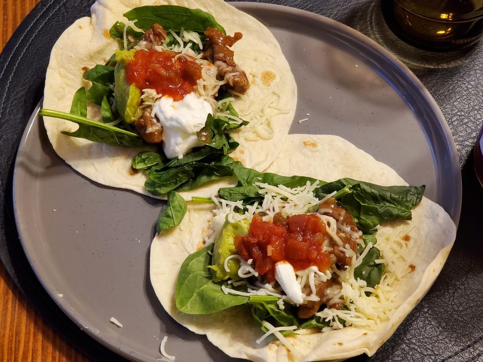 two tacos on flour tortillas with veggies, sour cream, and salsa as toppings