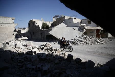 Men ride a motorcycle near damaged buildings in the rebel held Douma neighbourhood of Damascus, Syria September 22, 2016. REUTERS/Bassam Khabieh