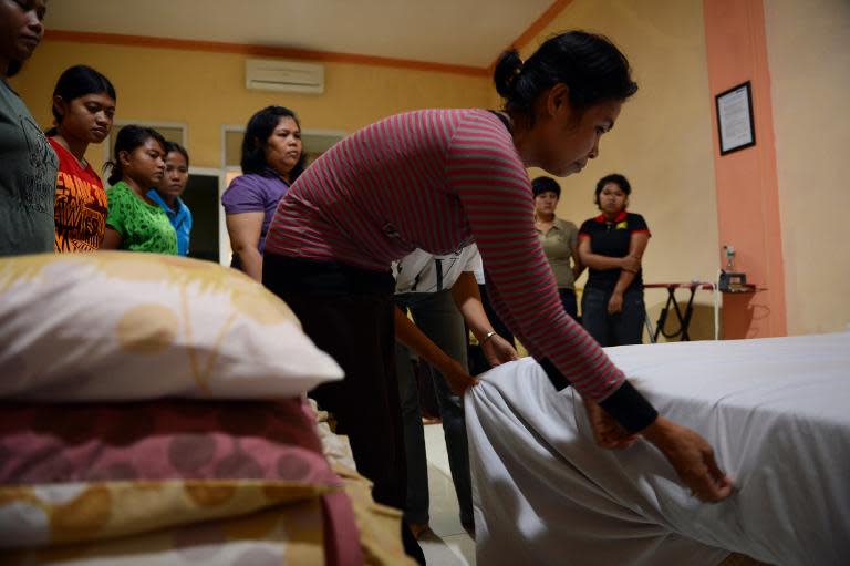 An Indonesian maid learns to fix a bed in Jakarta, during a class for a group of maids undergoing training at a private recruitment agency, in January 2014