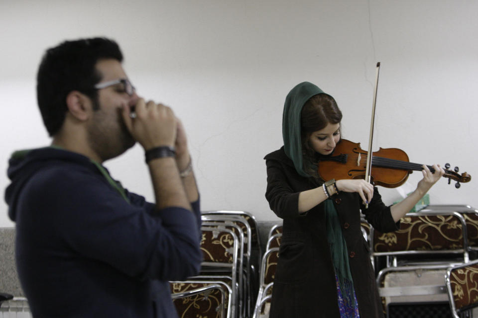 In this picture taken on Friday, Feb. 1, 2013, female Iranian violinist Nastaran Ghaffari and Danial Izadi with his harmonica practice for their band called "Accolade" in a basement of a house in Tehran, Iran. Headphone-wearing disc jockeys mixing beats. It’s an underground music scene that is flourishing in Iran, despite government restrictions. (AP Photo/Vahid Salemi)