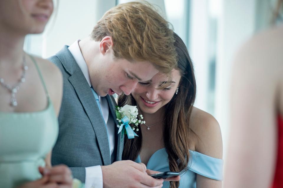 From left, Nico Catalde, 17, and Lexi Rich, 16, text, on May 21, 2022, at the start of the Enchanted Forest-themed McDowell High School held at the Bayfront Convention Center in Erie. 