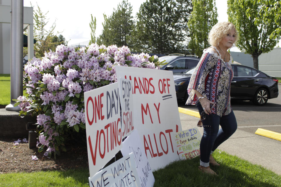 Oregon Voter and protester Janet Bailey walks near signs criticizing election problems in Clackamas County, Oregon, on Wednesday, May 25, 2022. Voters in an Oregon county where a ballot-printing error has delayed election results for nearly two weeks have elected the same county clerk five times in the past 20 year despite missteps that impact two previous elections and cost taxpayers $100,000. Opponents have repeatedly tried to unseat Clackamas County Clerk Sherry Hall, who was first elected in 2002, following elections errors in 2004, 2010, and 2011 and a state vote-tampering investigation in 2012.(AP Photo/Gillian Flaccus)