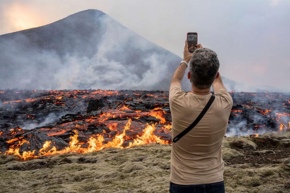 PHOTO: A man takes pictures as lava emerges from a fissure of the Fagradalsfjall volcano near the Litli-Hrutur mountain, southwest of Reykjavik, Iceland, July 10, 2023. (Marco Di Marco/AP)