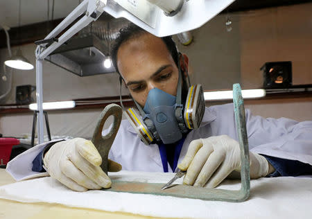 An Egyptian scientist works on restoring a piece of the second Khufu boat at a temporary laboratory set up next to the Great Pyramids, where it was discovered, in Giza, Egypt, March 29, 2017. REUTERS/Mohamed Abd El Ghany