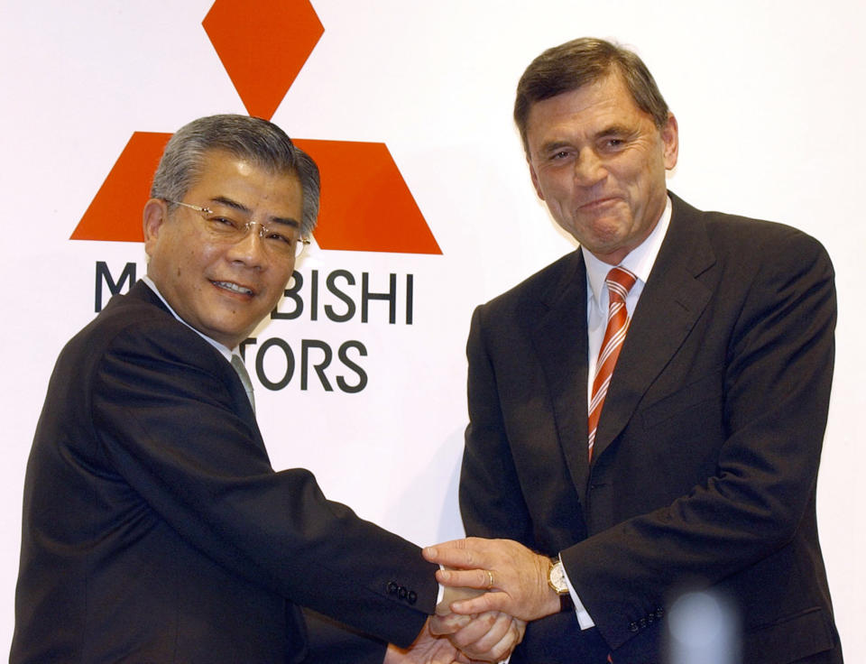 FILE - In this March 27, 2002, file photo, Rolf Eckrodt, then Daimler Chrysler AG executive sent into lead a turnaround at scandal-tarnished Mitsubishi Motors Corp., right, shakes hands with then Mitsubishi President Takashi Sonobe during a news conference in Tokyo announcing that Eckrodt was named president of the Japanese automaker succeeding Sonobe. German-U.S. automaker Daimler Chrysler bought a 37 percent stake in Tokyo-based Mitsubishi Motors Corp. in 2000, but the alliance felt rocky from the start. Mitsubishi Motors was embroiled in a years long scandal over its systematic cover-up of auto defects. (AP Photo/Tsugufumi Matsumoto, File)