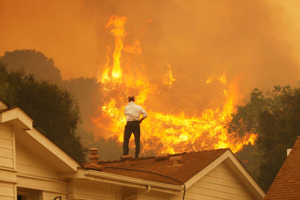 A man on a rooftop looks at approaching flames as the Springs fire continues to grow on May 3, 2013 near Camarillo, Calif.