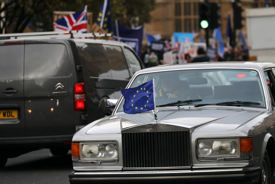 A Rolls Royce flying an EU flag on its bonnet drives past protestors opposite the Houses of Parliament in London, Tuesday, Jan. 15, 2019. Britain's Prime Minister Theresa May is struggling to win support for her Brexit deal in Parliament. Lawmakers are due to vote on the agreement Tuesday, and all signs suggest they will reject it, adding uncertainty to Brexit less than three months before Britain is due to leave the EU on March 29. (AP Photo/Frank Augstein)