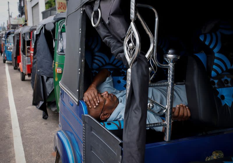 A driver of an autorickshaw sleeps inside his rickshaw while waiting in a line to buy petrol at a fuel station, in Colombo