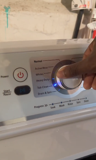 A hand is turning a dial on a washing machine, selecting a wash setting