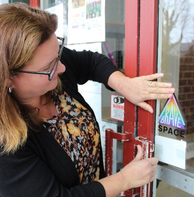 Martin Luther King Jr Community Center Executive Director Heather Hole Stout applies a "Brave Space" sticker to a door at the center.
