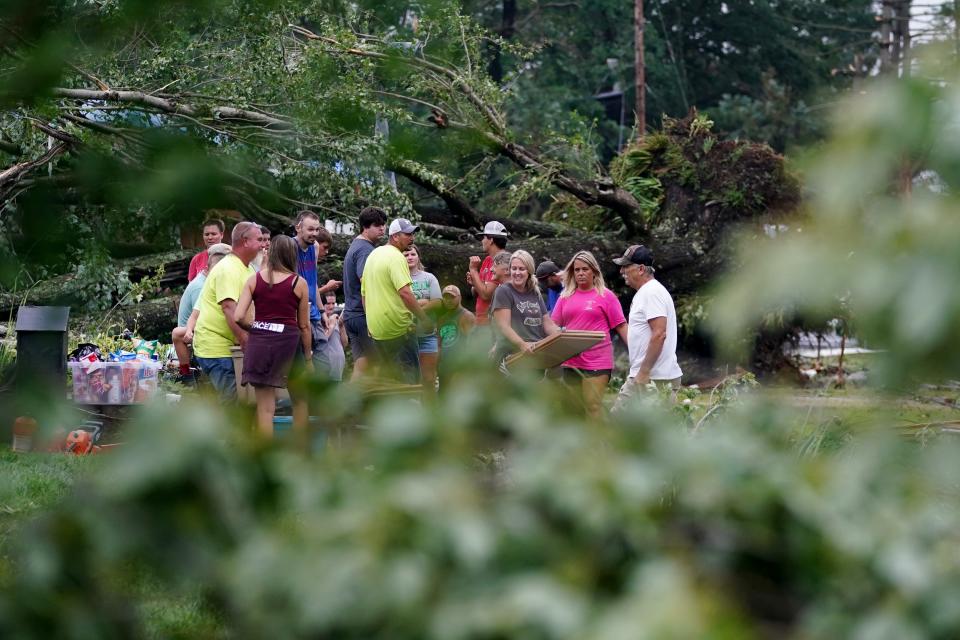 Neighbors work to clear debris and clean up damage along Wood Street following an EF2 tornado, that his Goshen Township Wednesday.