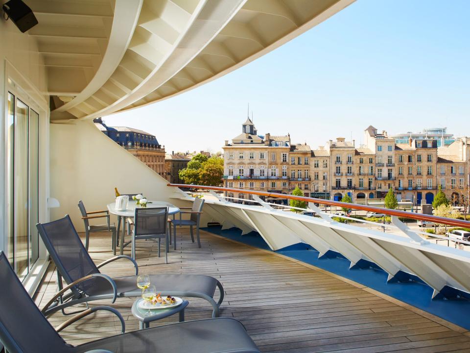 A balcony on the The World with lounge chairs and a white railing overlooking a nearby city.