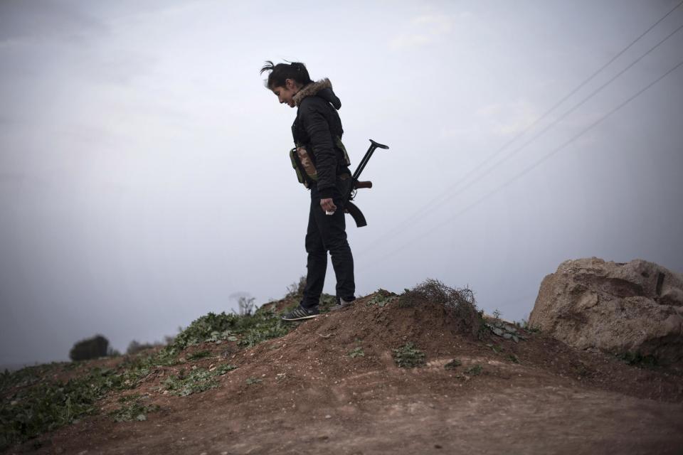 FILE - In this Sunday, March 3, 2013 file photo, a Kurdish female member of the Popular Protection Units stands guard at a checkpoint near the northeastern city of Qamishli, Syria. Nearly three years after the crisis began, Syria's government and opposition are set to meet in Geneva this week for the first direct talks aimed at ending the conflict. (AP Photo/Manu Brabo, File)