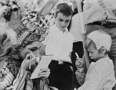 <p>Elizabeth, who did most of her dazzling makeup for the film <em>Cleopatra</em>, is seen fixing her eyeliner while her two sons look on. </p>