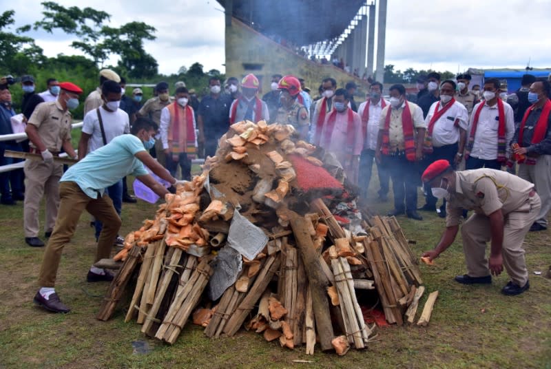 Assam Police personnel burn seized drugs during a ceremony at a playground in Karbi Anglong