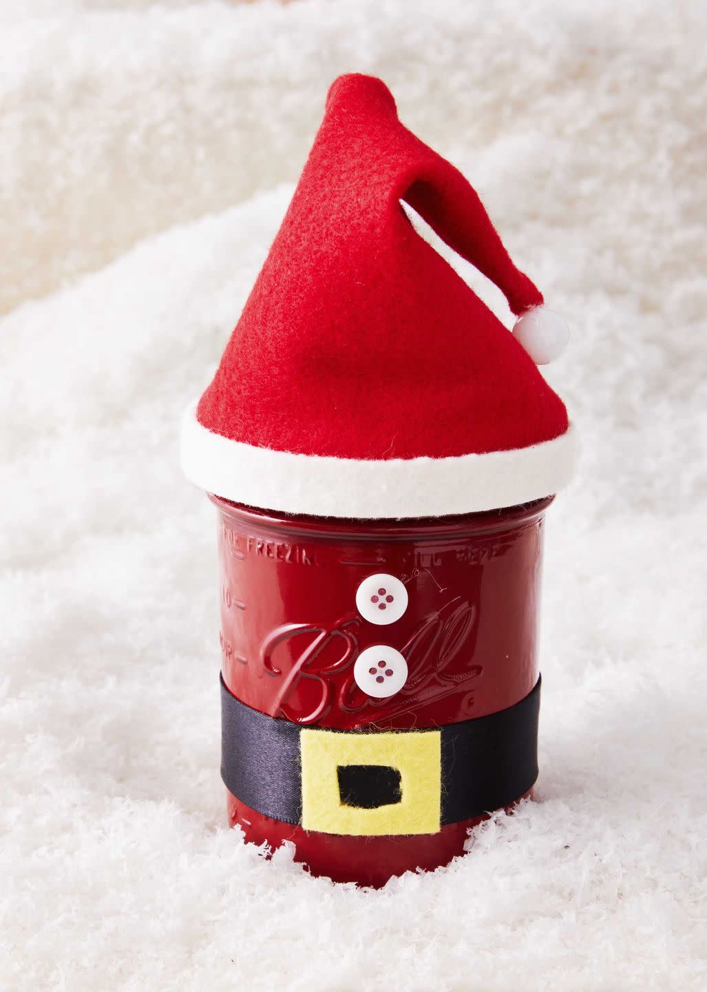 a mason jar decorated to look like a santa outfit with a hat made from red felt and a belt made from black ribbon and yellow felt