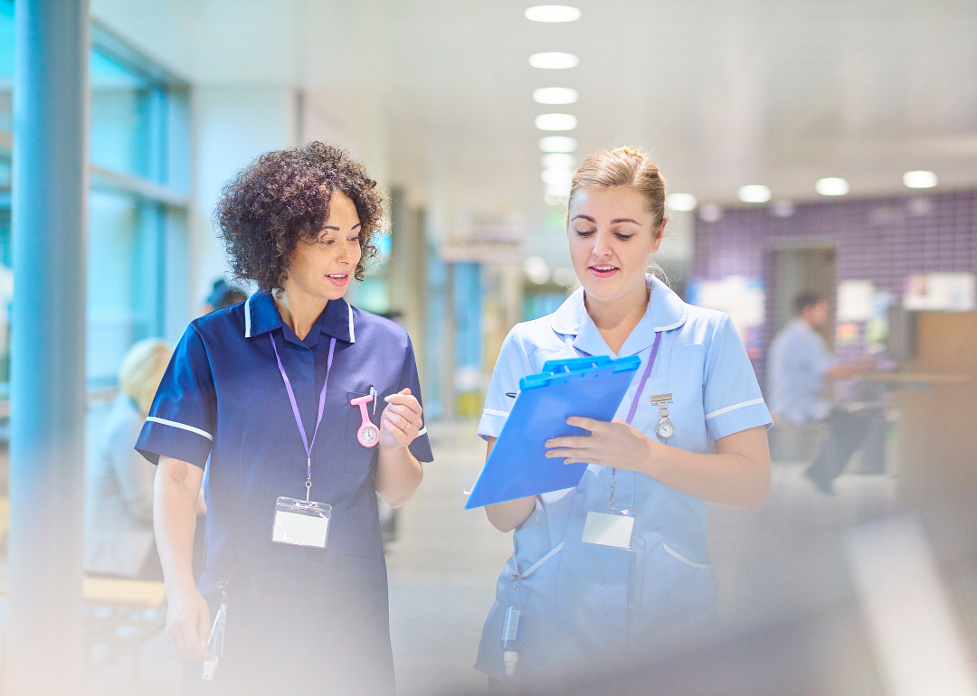 A nurse talking with an assistant in the hospital hallway.