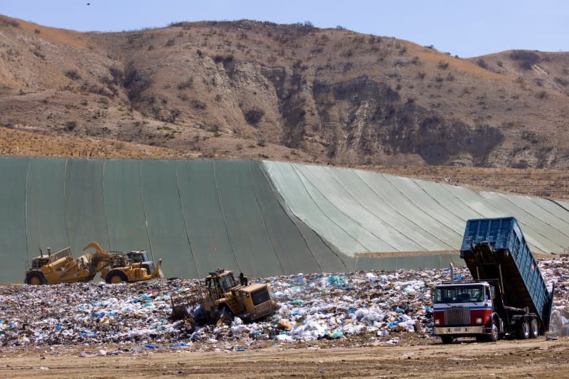 Workers use heavy machinery to move trash and waste at the Frank R. Bowerman landfill in California