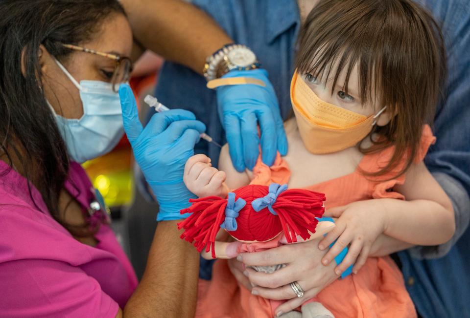 Flora Grace Brown, 1, holds onto her doll as she gets a COVID-19 vaccine at Children's Hospital New Orleans. Children under 5 can now get a series of free COVID-19 vaccine shots. They're available in Knox County.