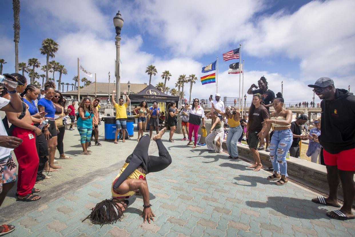 A crowd applauds a dancing man as he spins on the ground.