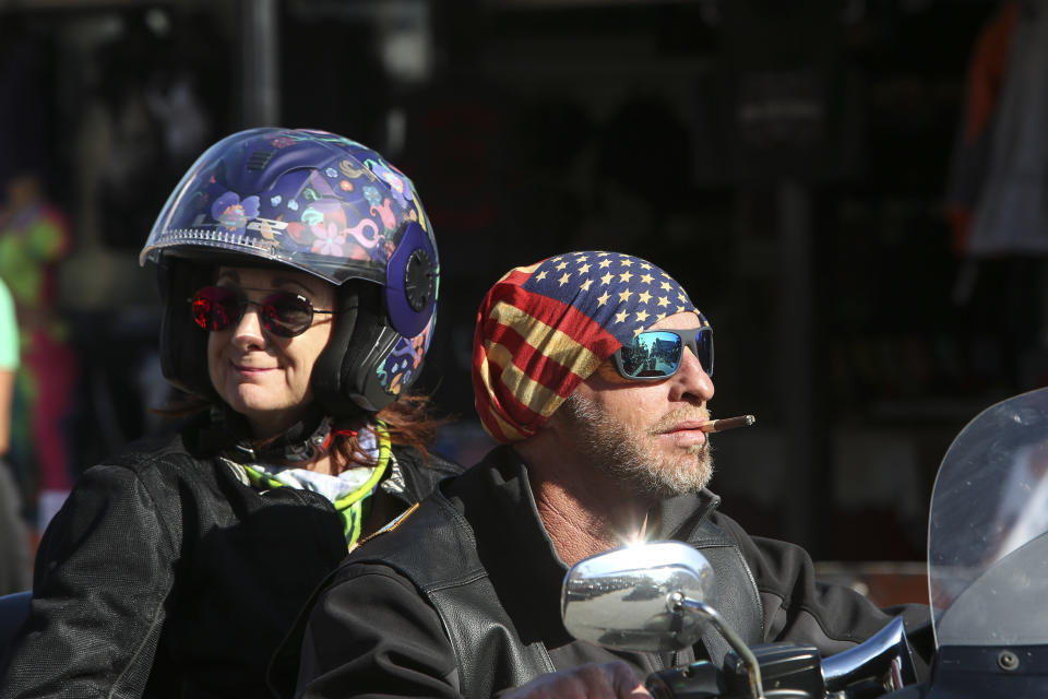 Two people ride down Main Street in Daytona, Fla., during the start of Bike Week on Friday, March 5, 2021. (Sam Thomas /Orlando Sentinel via AP)