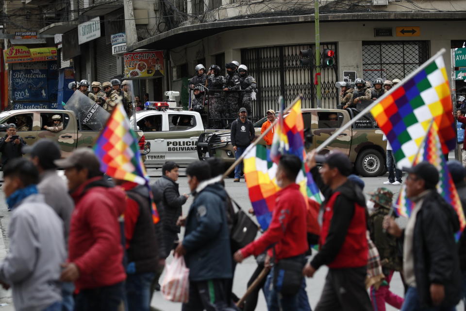 Police patrol on the sidelines of a march by supporters of former President Evo Morales, arriving from El Alto and entering La Paz, Bolivia, Tuesday, Nov. 12, 2019. Former President Evo Morales, who transformed Bolivia as its first indigenous president, flew to exile in Mexico on Tuesday after weeks of violent protests, leaving behind a confused power vacuum in the Andean nation. (AP Photo/Natacha Pisarenko)
