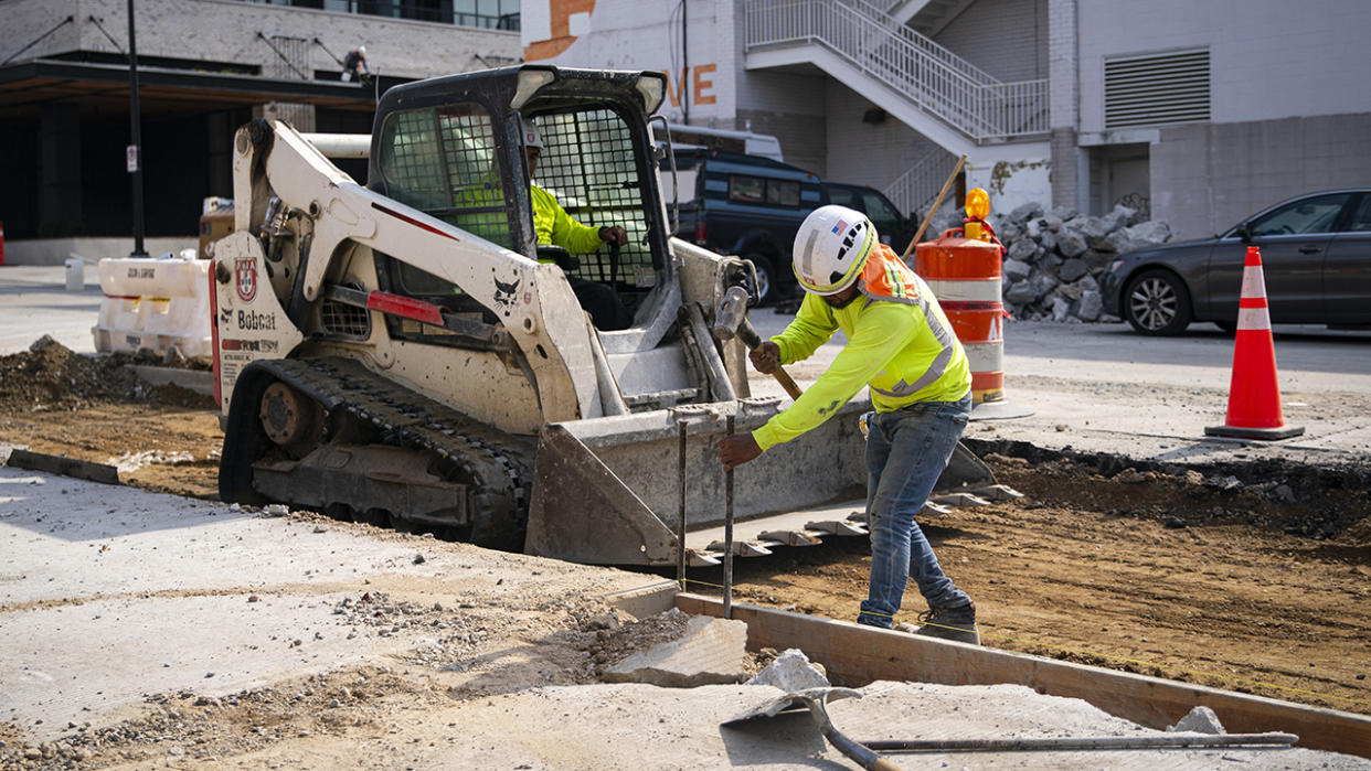 A construction worker hammers a beam