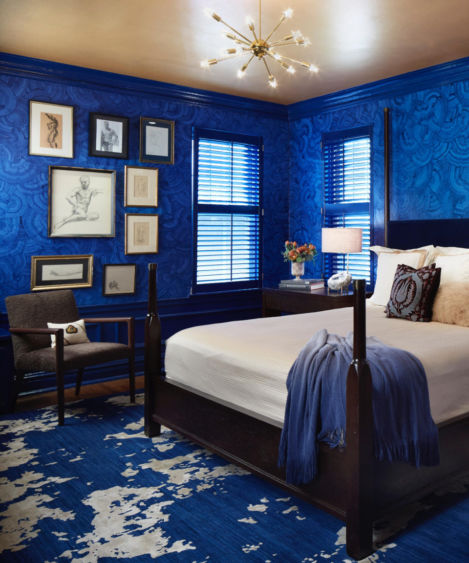 how to make a bedroom darker, bedroom with blue wallpaper, blue rug, mahogany bed, blue blinds, artwork