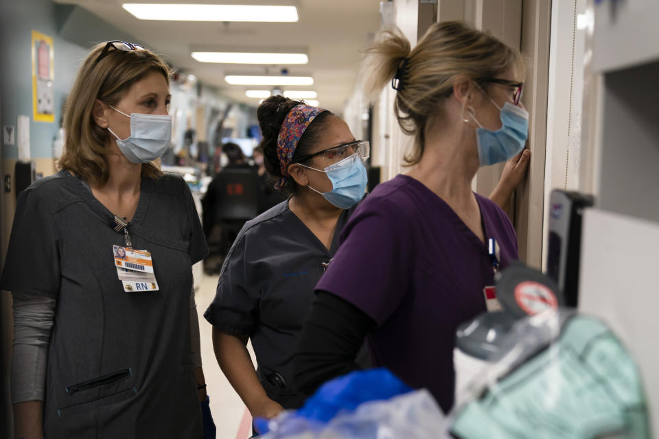 ARCHIVO - En esta fotografía de archivo del 19 de noviembre de 2020, de izquierda a derecha, la enfermera Kristina Shannon, la capellana Andrea Cammarota y la enfermera Cathy Carter observan a trabajadores médicos que intentan reanimar a un paciente que dio positivo al coronavirus, en el Centro Médico Providence Holy Cross en el sector Mission Hills de Los Ángeles. (AP Foto/Jae C. Hong, archivo)