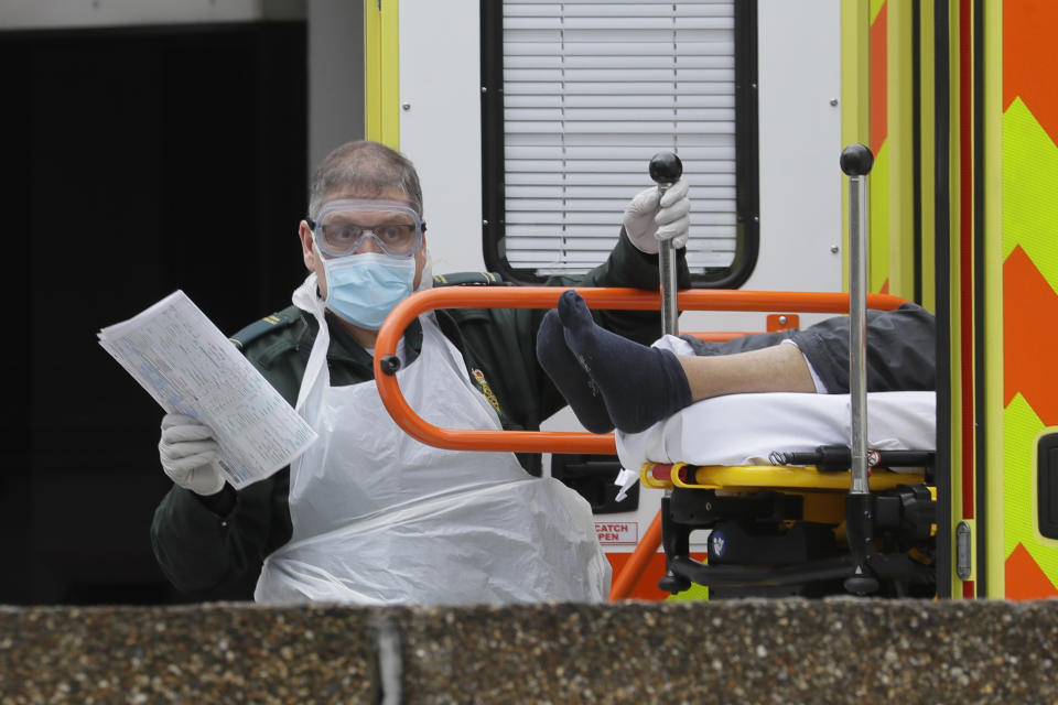 FILE - In this Tuesday, March 31, 2020 file photo a patient is helped from an ambulance upon arrival at St Thomas' Hospital, one of the many hospitals dealing with coronavirus patients in London. Britain's National Health Service, cornerstone of the nation's post-war welfare state, may be stretched to the breaking point in coming weeks as hospitals brace for an expected tsunami of critically ill patients when the coronavirus pandemic reaches its peak across the United Kingdom. (AP Photo/Kirsty Wigglesworth, File)