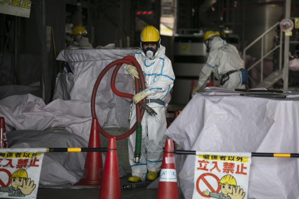 日本政府今（13日）宣布，正式決議將福島核廢水稀釋後，排入海中，照片中是一名身穿危險品防護衣的工人，拿著軟管，在福島第一核電廠的水處理設施工作。圖片來源：AP。