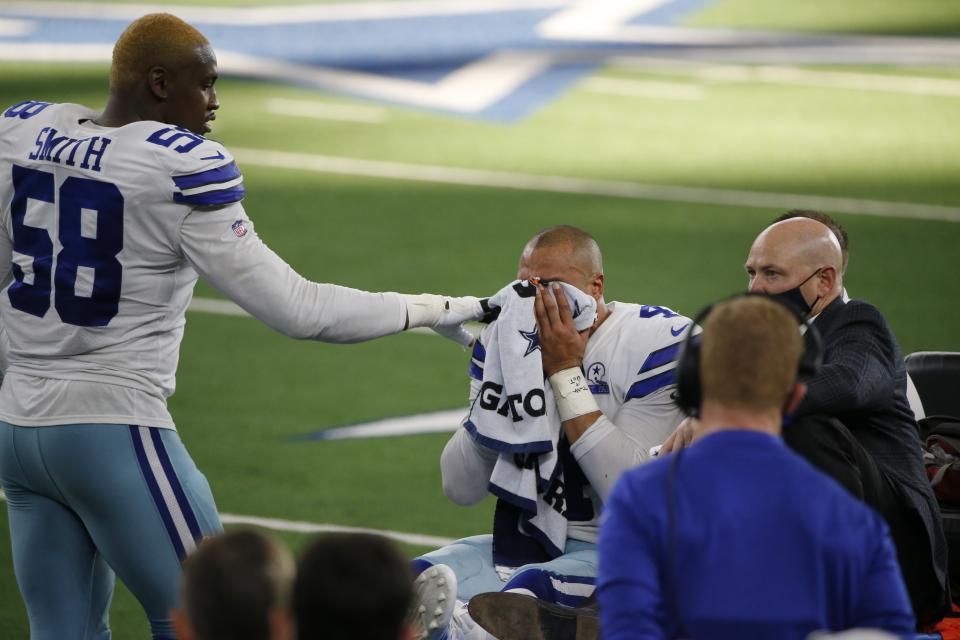 Dallas Cowboys defensive end Aldon Smith (58) comforts quarterback Dak Prescott (4) as he is carted off the field after suffering a lower right leg injury running the ball against the New York Giants in the second half of an NFL football game in Arlington, Texas, Sunday, Oct. 11, 2020. (AP Photo/Michael Ainsworth)