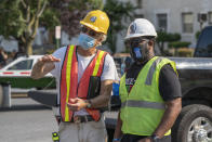 In this photo provided by Sanjay Suchak, Richmond sculptor Paul DiPasquale, left, talks with Devon Henry during the removal of the J.E.B. Stuart statue on Monument Avenue on Tuesday July 7, 2020 in Richmond, Va. Henry's company won the contract to remove the Confederate Statues from the city of Richmond. (Sanjay Suchak via AP)