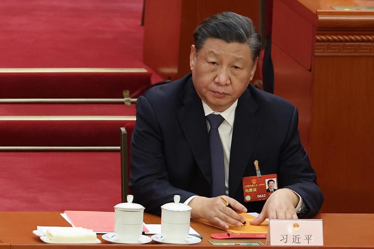Xi Jinping sitting at a table with a peng and paper.