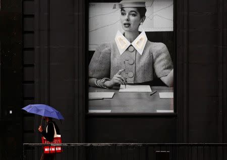 A man shelters under an umbrella as he passes a display at the Old Street roundabout dubbed "Silicon Roundabout" in London in this May 28, 2013 file photo. REUTERS/Luke Macgregor/Files