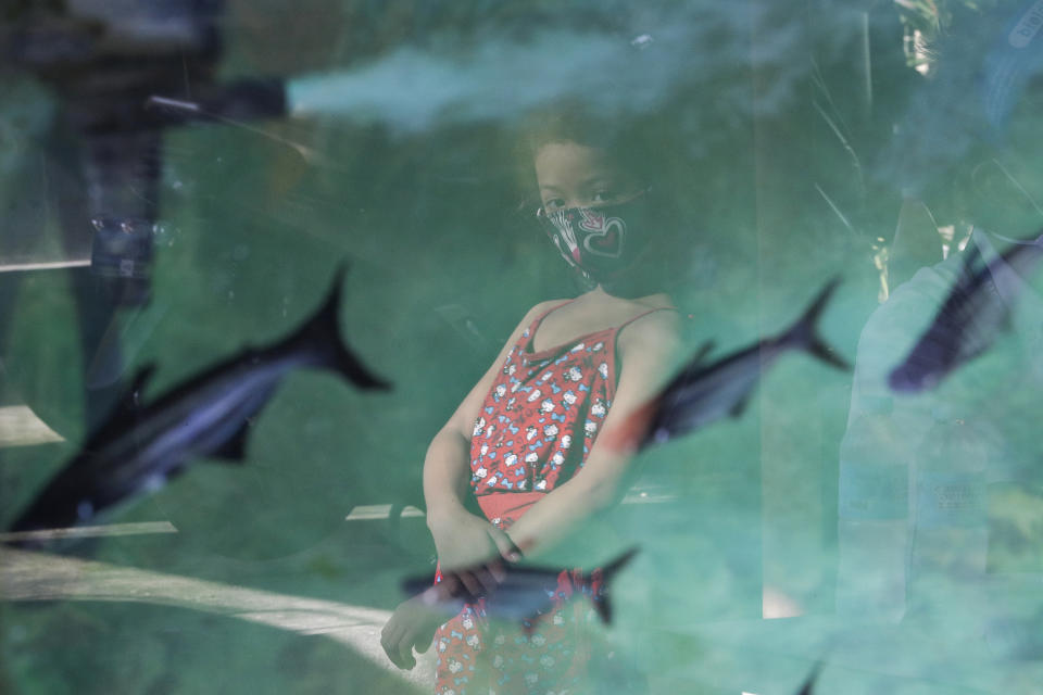 Filipino girl Yuna Recio wears a protective masks to prevent the spread of the new coronavirus as she looks at an aquarium at the Tandang Sora jeepney terminal in Quezon city, Philippines on Monday, Oct. 5, 2020. (AP Photo/Aaron Favila)