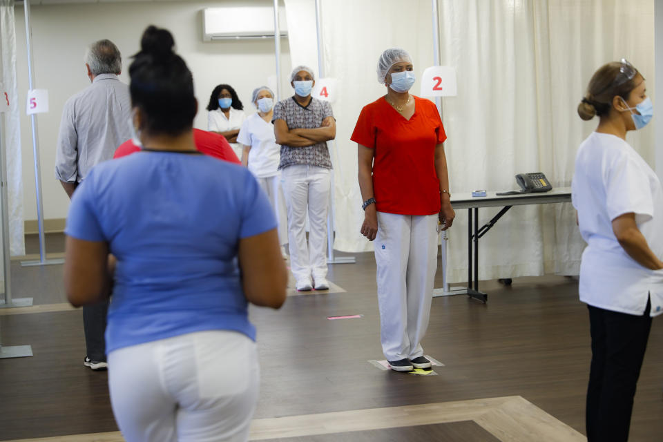 On-campus staff working on the grounds of the Hebrew Home at Riverdale wait to be tested for COVID-19 by nasal swab before they can begin their shifts, Friday, June 12, 2020, in the Bronx borough of New York. The testing operation began on May 20 and processes an average of 350 swab tests a day with a 24-hour turnaround time on results. All staff members, including construction contractors, security personnel, food services and maintenance members, in addition to critical medical staff, are tested twice a week. (AP Photo/John Minchillo)