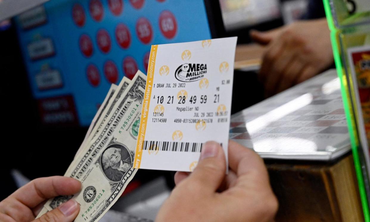 <span>A person buys a Mega Millions lottery ticket at a store in Arlington, Virginia, in 2022.</span><span>Photograph: Olivier Douliery/AFP/Getty Images</span>