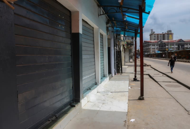 A man walks beside closed shops in a nearly deserted wholesale market during lockdown by the authorities to limit the spread of coronavirus disease (COVID-19), in Lagos