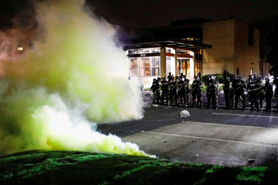 Protests: Tear gas is seen as officers stand guard outside Brooklyn Center Police Department (REUTERS)