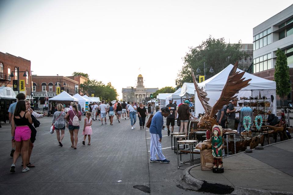 Community members stroll past booths on Iowa Avenue during Iowa Arts Festival, Friday, June 3, 2022, in Iowa City, Iowa.