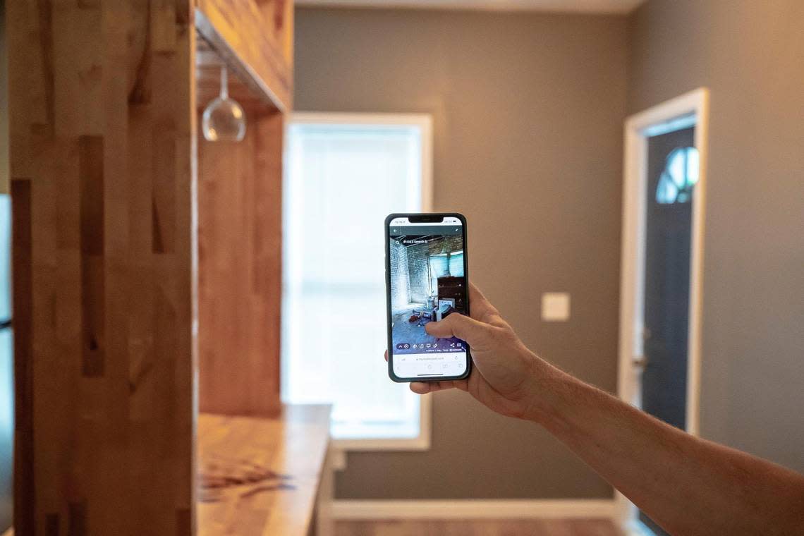 Jeff Moore, a Lexington real estate investor, holds a phone displaying a photograph taken in the same place before renovations where undertaken on a home on East Seventh Street in Lexington, Ky., on Tuesday, Aug. 30, 2022.