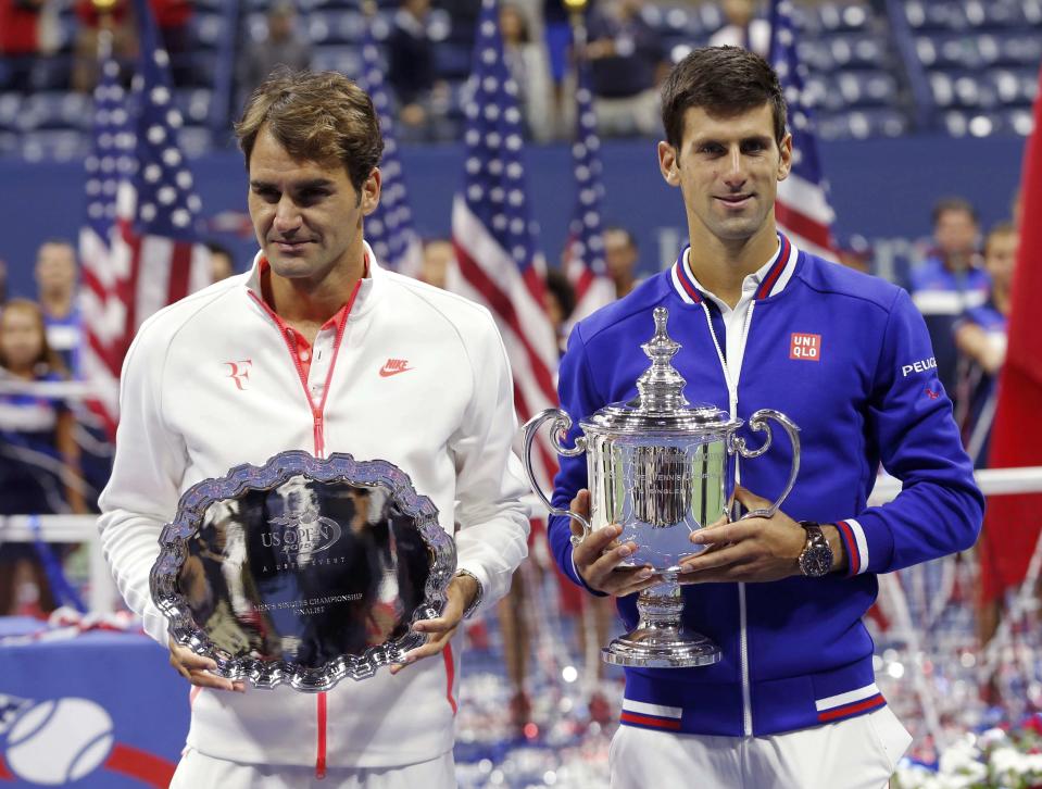 Roger Federer of Switzerland (L) hold his runner-up prize as Novak Djokovic of Serbia holds the U.S. Open trophy after Djokovic won their men's singles final match at the U.S. Open Championships tennis tournament in New York, September 13, 2015. REUTERS/Mike Segar
