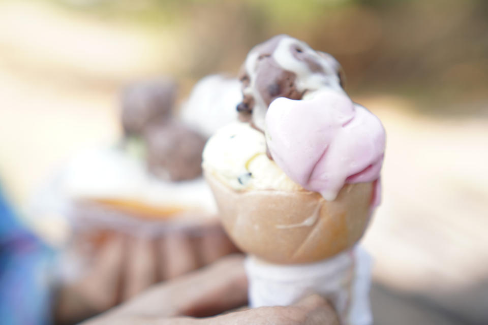 Person holding a cone with multiple scoops of ice cream