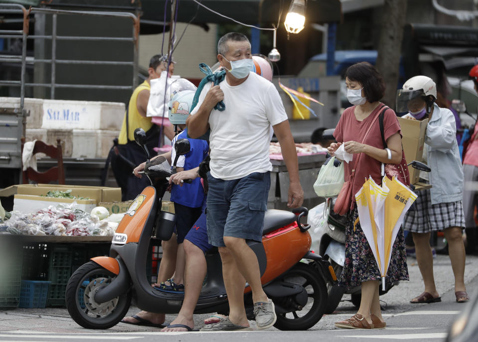 People wear face masks to help protect against the spread of the coronavirus after the COVID-19 alert rose to level 3 in Taipei, Taiwan, Friday, July 30, 2021. Taiwan's economic growth slowed to 7.5% over a year earlier in the latest quarter as anti-coronavirus controls depressed consumer spending and manufacturing. (AP Photo/Chiang Ying-ying)